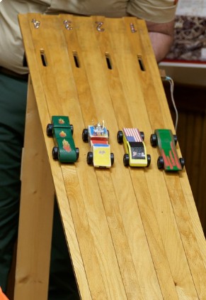 Pinewood Derby cars on a wooden track