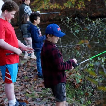 Scouts fishing beside a wooded stream